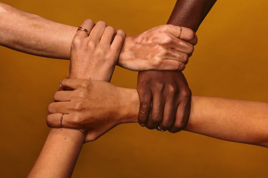 women with different skin tones holding hands