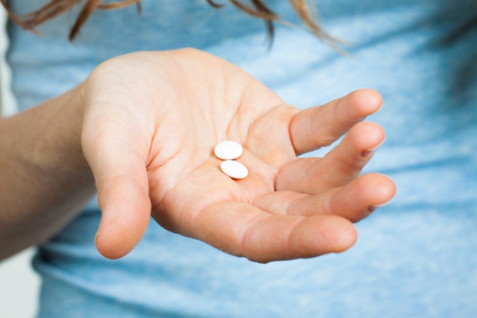Close-up shot of a hand holding two white pills.