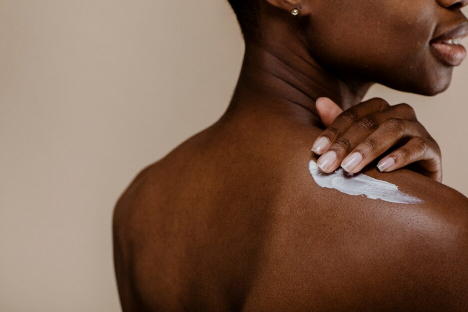 woman rubs cream into shoulders
