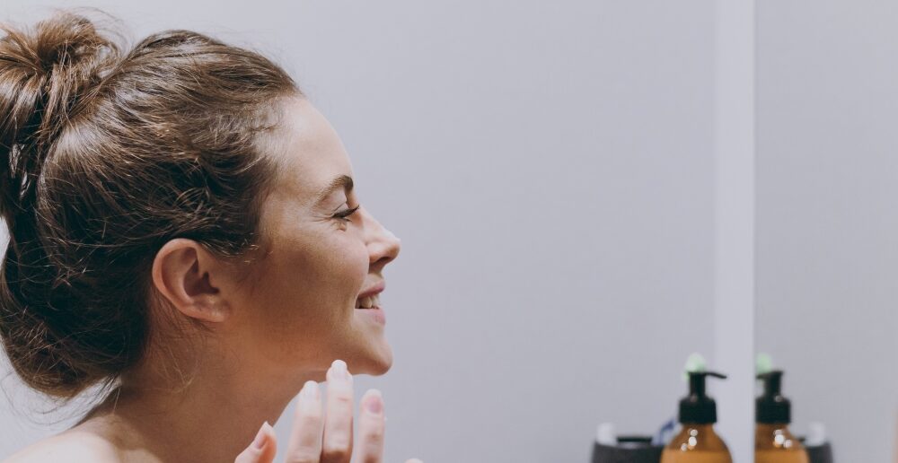 woman looking in the mirror skincare routine