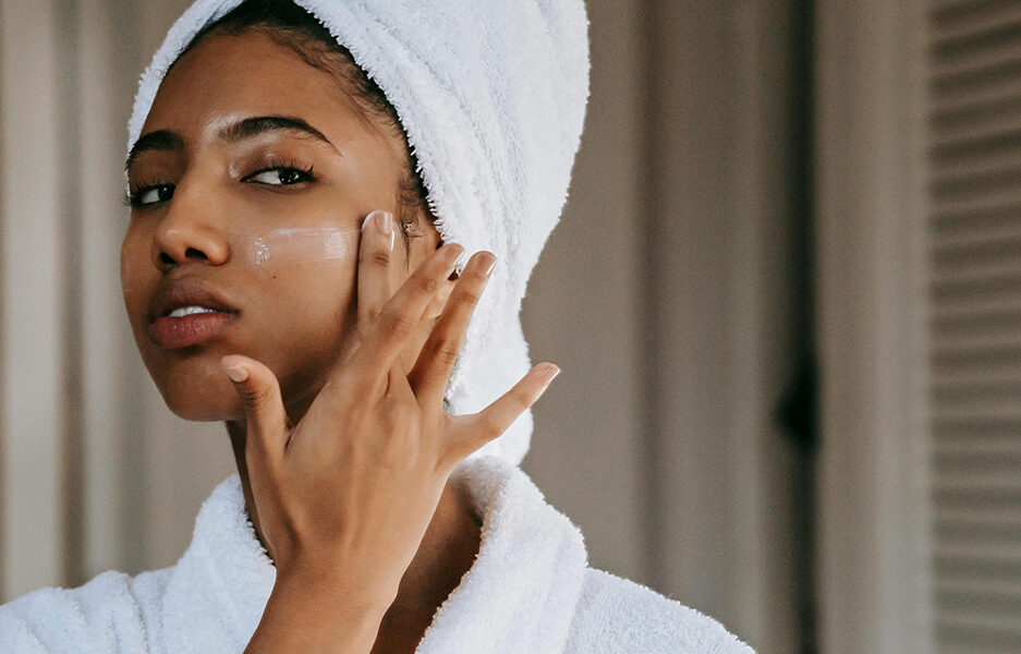 woman applying skincare in bathrobe